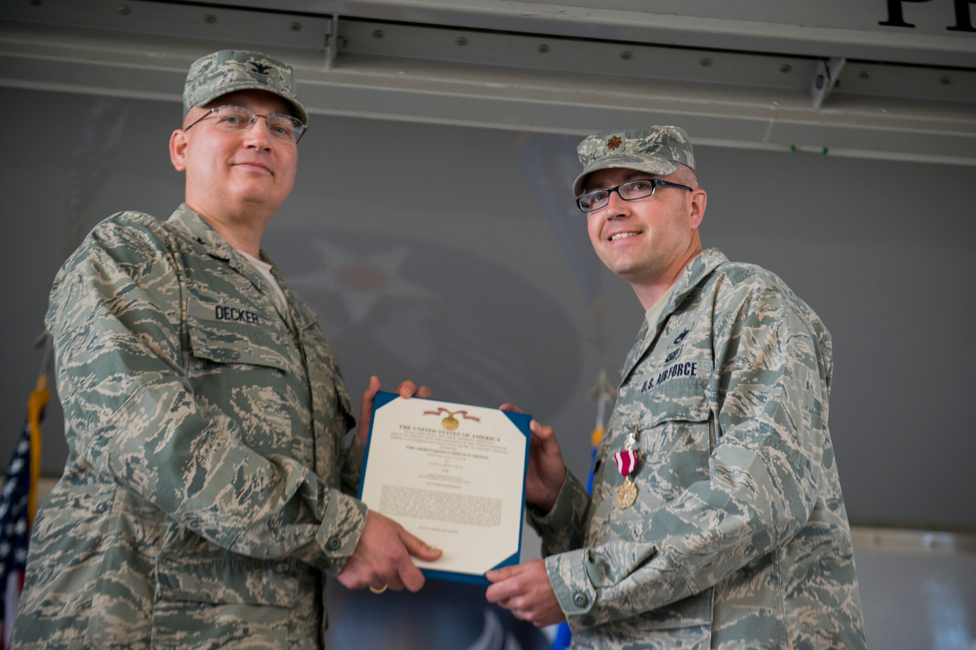U.S. Air Force Col. Jeffrey Decker, 23d Maintenance Group commander (left), presents a Meritorious Service Medal certificate to Maj. Aaron Buck, 23d Maintenance Operations Squadron commander, during the 23d MOS inactivation ceremony May 15, 2013, at Moody Air Force Base, Ga. Buck arrived at Moody to lead the unit in June 2011. (U.S. Air Force photo by Staff Sgt. Jamal D. Sutter/Released)