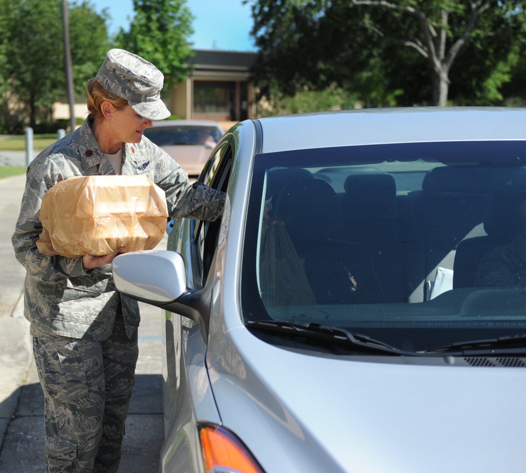 U.S. Air Force Maj. Michele Holderness, 23d Medical Support Squadron commander, hands out food during the Drive-Thru Spouse Deployed Dinner at Moody Air Force Base, Ga., May 14, 2013.Volunteers handed out more than 200 meals to spouses of deployed Moody Airmen. ( U.S. Air Force photo by Staff Sgt. Melissa K. Mekpongsatorn/Released)
