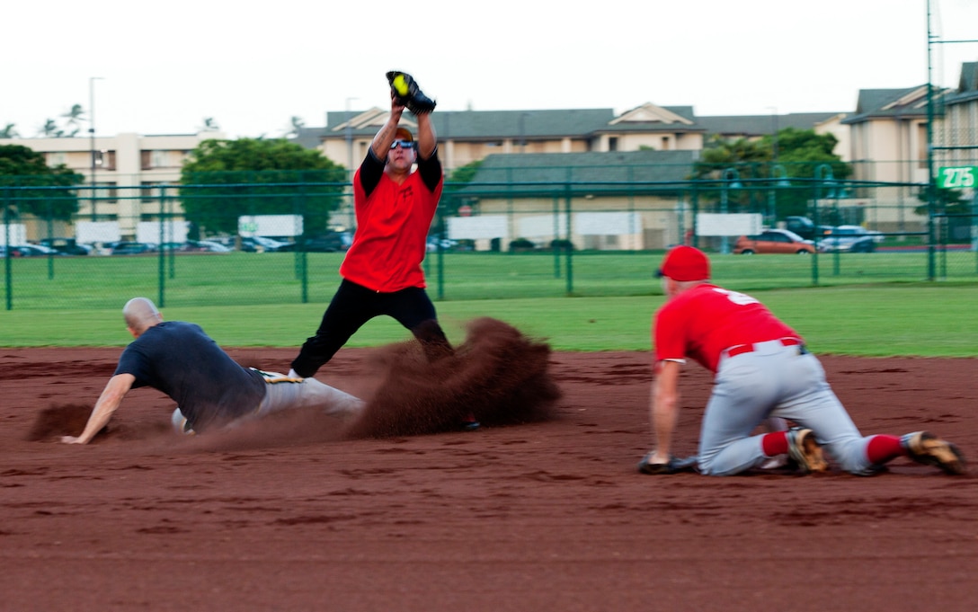 Marine Light Attack Helicopter Squadron 367 Scarface shortstop Christopher Manuel catches the ball as a Marine Aviation Logistics Squadron 24 Warrior slides into second base during an intramural softball league game at Annex Field, May 14, 2013. The game ended 11-8 with the Warriors taking the win from Scarface. (U.S. Marine Corps photo by Lance Cpl. Nathan Knapke)
