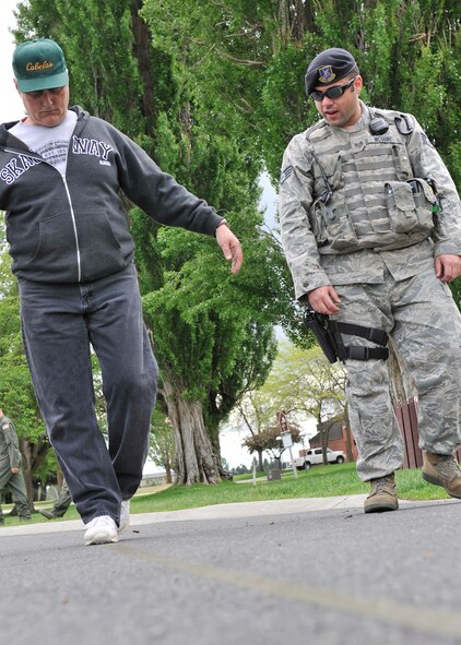 Lt. Cmdr. Kenneth Simmet, 92nd Medical Operations Squadron Mental Health Flight deputy commander, performs a field sobriety test administered by Staff Sgt. Stephen McGuire, 92nd Security Forces Squadron installation patrolman, during a simulated driving under the influence demonstration at Fairchild Air Force Base, Wash., May 16, 2013. (U.S. Air Force photo by Staff Sgt. Michael Means/Released)