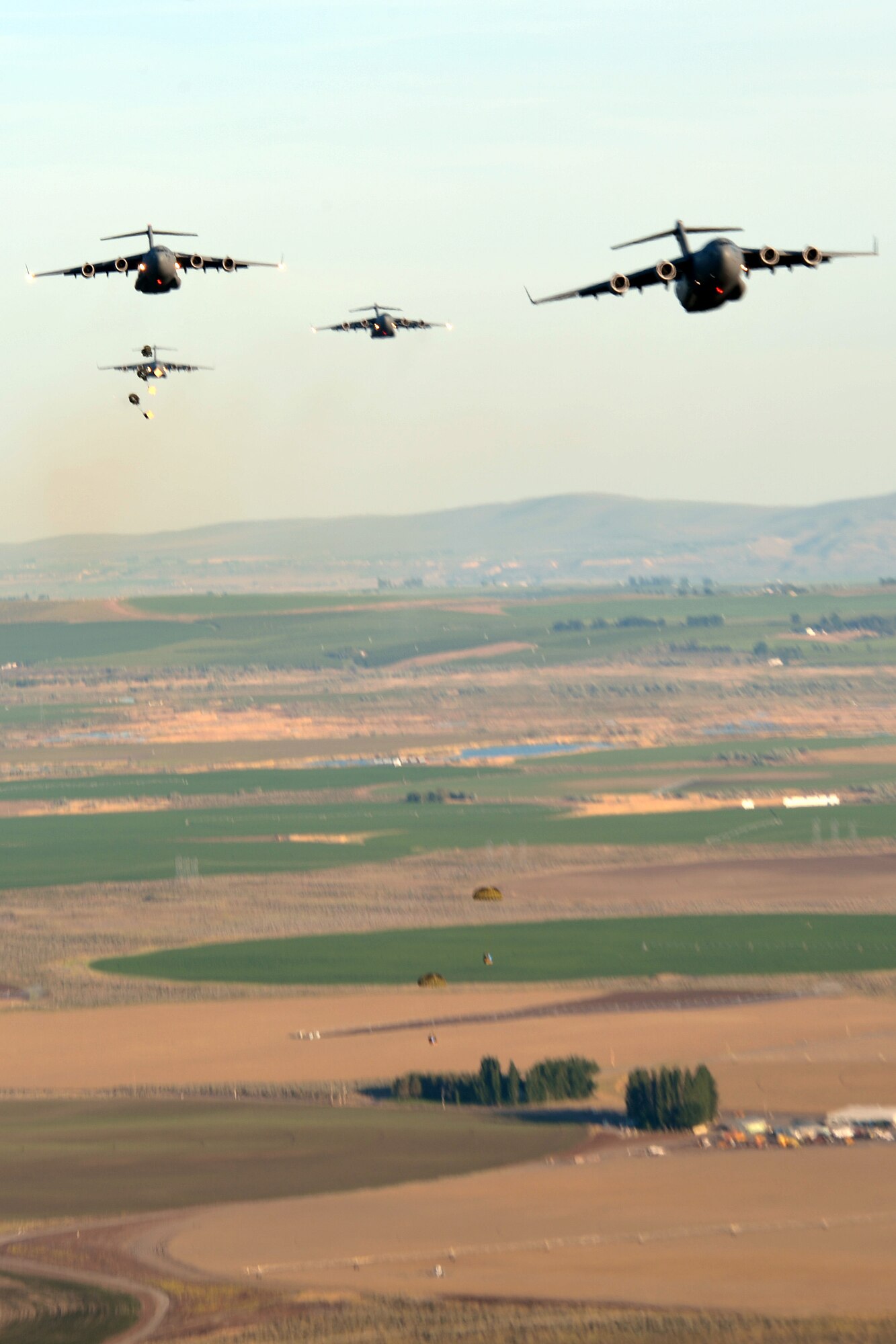 C-17 Globemaster III aircraft from Joint Base Lewis-McChord, Wash., airdrop pallets into a drop zone during a training mission May 14, 2013. Pilots maintained an altitude of approximately 1,000 feet for each airdrop. Pilots and loadmasters simulated and practiced dropping container delivery system bundles, heavy equipment and simulated personnel within the drop zone during formation flight. (U.S. Air Force photo/Airman 1st Class Jacob Jimenez)
