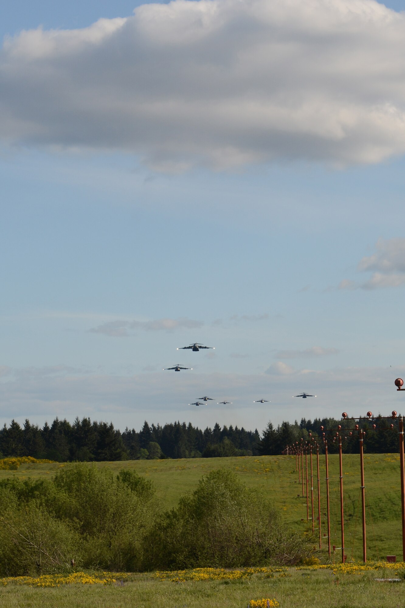 Seven C-17 Globemaster III aircraft perform a low-level pass May 14, 2013 over Joint Base Lewis-McChord, Wash. Airmen from the 7th Airlift Squadron flew a 7-ship formation flight lasting more than seven hours. Pilots had to maintain a distance of 2,000 feet away from each aircraft to avoid turbulence from each other. The aircraft were also required to be at a 500-foot difference in altitude from each other. (U.S. Air Force photo/Staff Sgt. Frances Kriss)