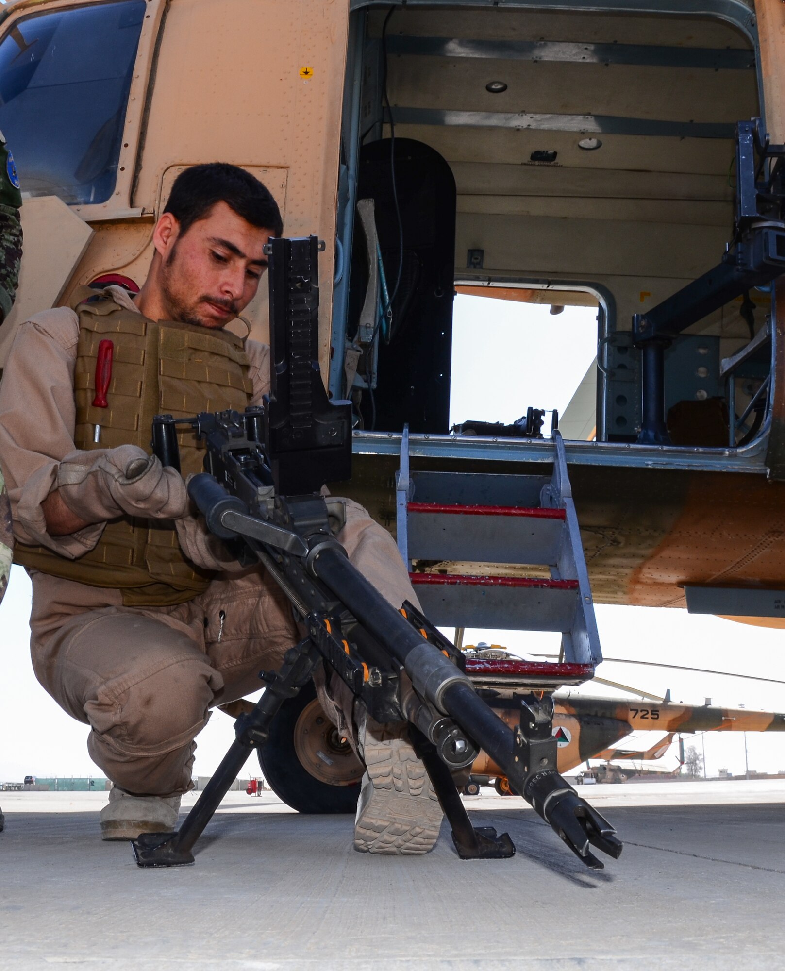 KANDAHAR, Afghanistan – An Afghan Air Force MI-17 helicopter aerial gunner inspects an M240 machine gun prior to flight at Kandahar Airfield May 6, 2013. There are two gunner positions aboard the helicopter, which are critical to support of aerial escort and air assault missions. (U.S. Air Force photo/1st Lt Tony Richardson)

