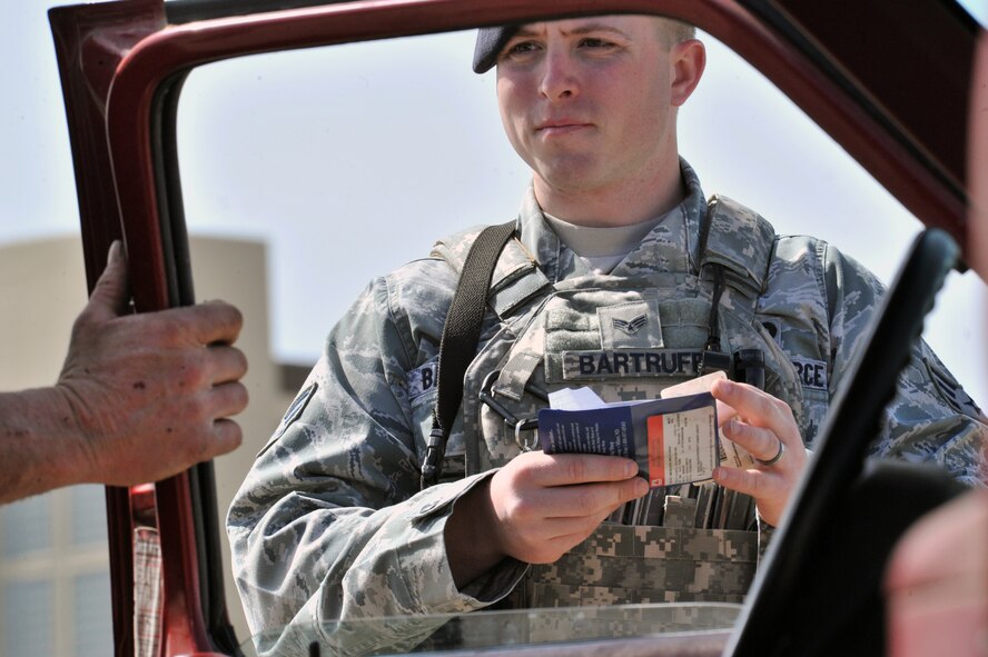 MINOT AIR FORCE BASE, N.D. -- Senior Airman Bryan Bartruff, 5th Security Forces Squadron response force team member, checks an identification card during a vehicle inspection here, May 13. The primary mission of the 5th SFS is to provide 24-hour law enforcement and security services for the 5th Bomb Wing and all tenant units assigned to the base. (U.S. Air Force photos/Senior Airman Brittany Y. Auld)