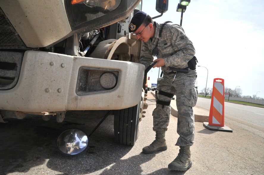 MINOT AIR FORCE BASE, N.D. -- Airman 1st Class Domingo Perez Jr., 5th Security Forces Squadron response force team member, uses a reflective mirror to inspect the undercarriage of a vehicle here, May 13. The primary mission of the 5th SFS is to provide 24-hour law enforcement and security services for the 5th Bomb Wing and all tenant units assigned to the base. (U.S. Air Force photos/Senior Airman Brittany Y. Auld)