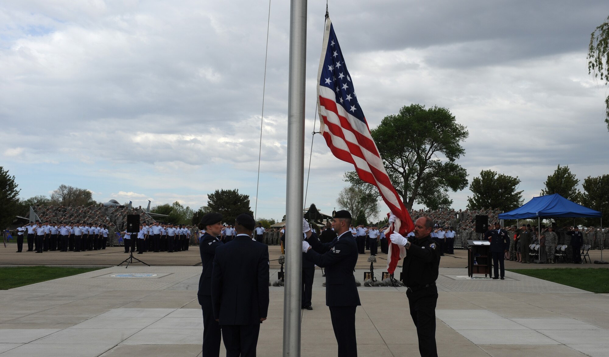 U.S. Air Force Airmen and a police officer lower the flag during retreat, May 15, 2013, at Mountain Home Air Force Base, Idaho.  Retreat signifies the end of the official duty day and serves as a ceremony for paying respect to the flag. (U.S. Air Force photo by Airman 1st Class Brittany A. Chase/Released)
