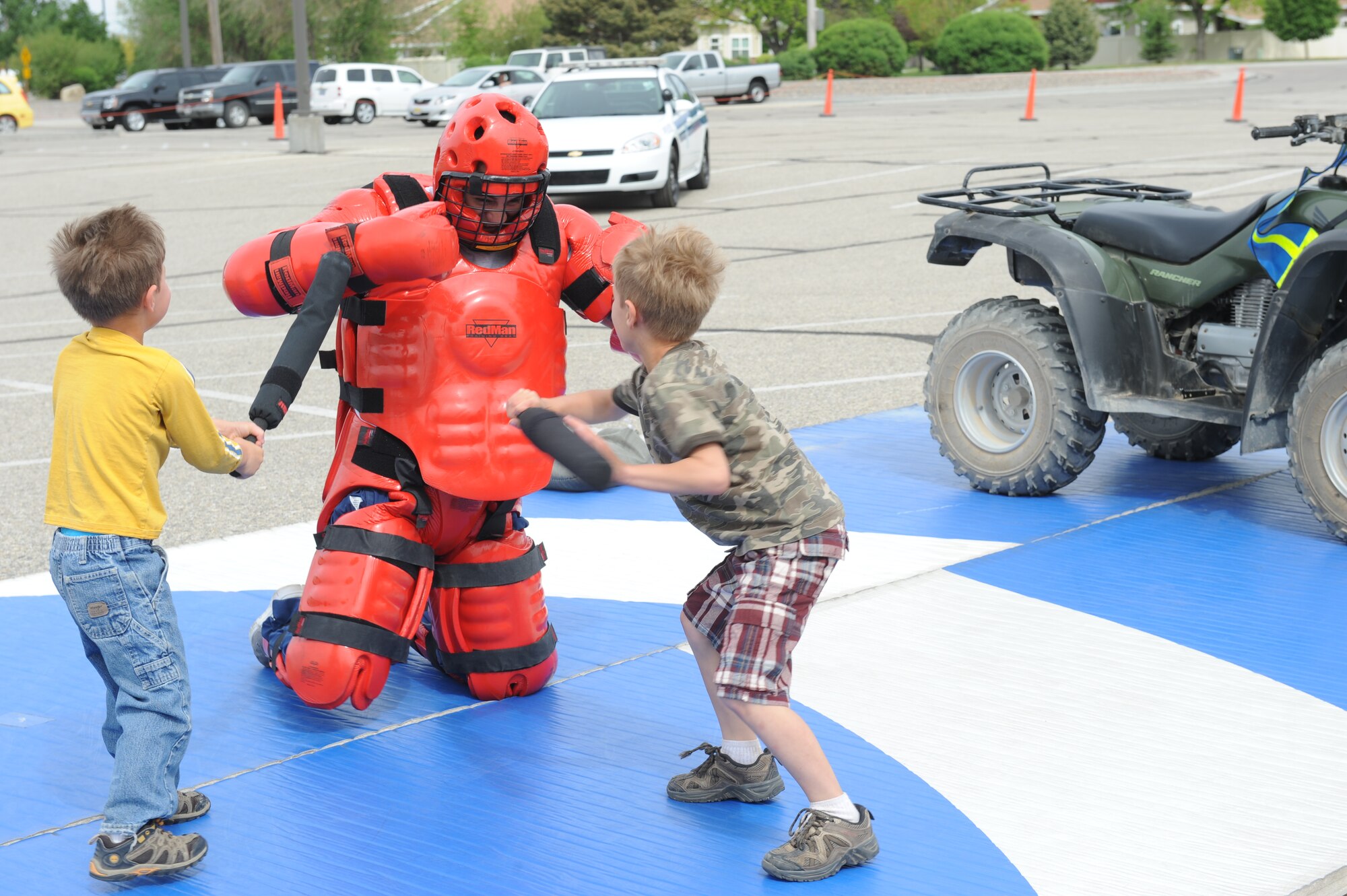 Justin (left) and Joshua Fischer attack a Defender wearing the Redman suit, May 15, 2013, at Mountain Home Air Force Base, Idaho. The Redman demonstration was a part of numerous police week actives that were held for community participation. (U.S. Air Force photo by Airman 1st Class Brittany A. Chase/Released)