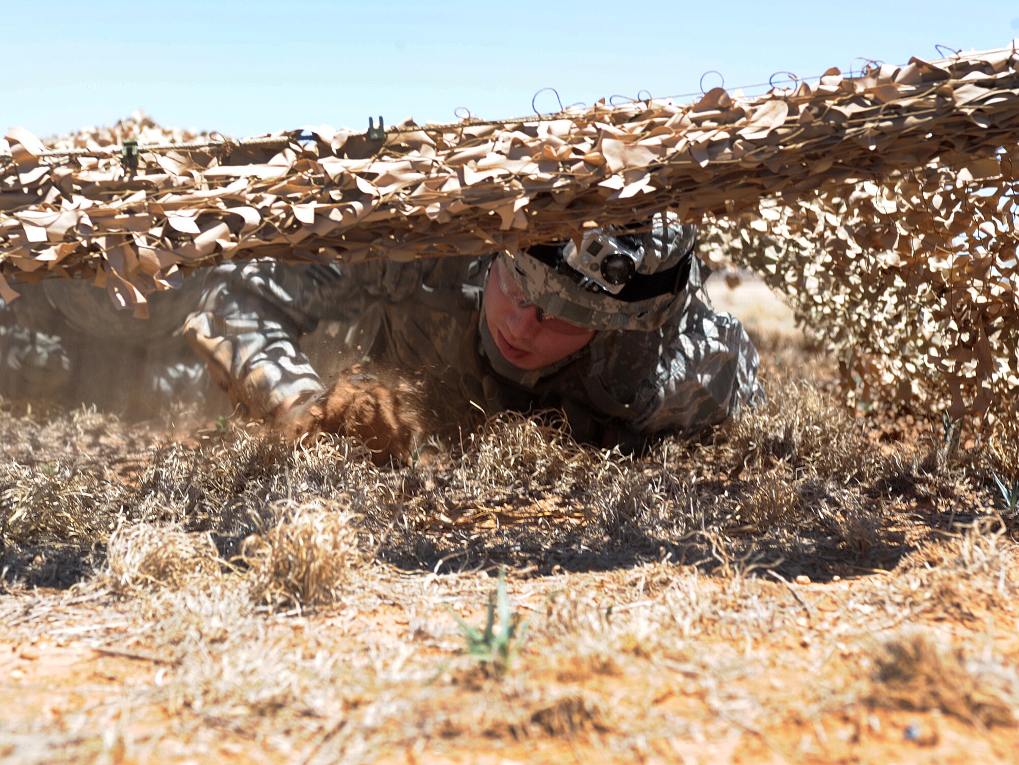 A U.S. Air Force security forces team member low crawls under a net while competing in an obstacle course during National Police Week activities at Cannon Air Force Base, N.M., May 13, 2013. National Police Week is an observance held to honor law enforcement officials for their sacrifices and hard work. (U.S. Air Force photo/Senior Airman Ericka Engblom) 