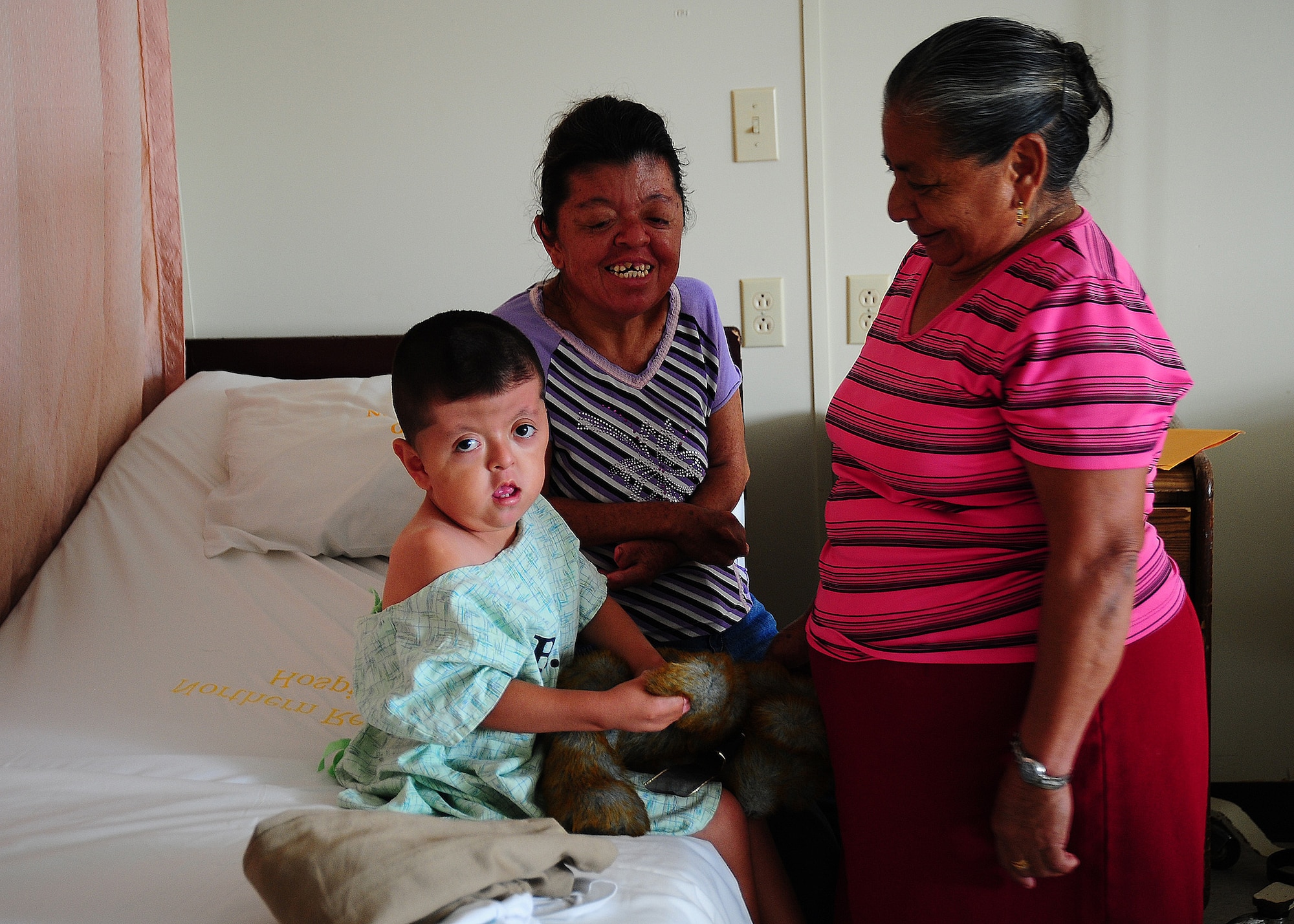 Isai Carrillo, a 4-year-old Belizean boy, holds a stuffed animal while sitting with his mother, Ruth, and his grandmother, Mercedes, prior to his surgery.  (Air Force photo by Tech. Sgt. Tony Tolley)