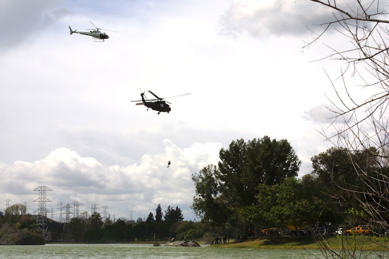 A civilian helicopter transporting a film crew circles above an Army Blackhawk helicopter as it executes a simulated rooftop evacuation on the set of the Army National Guard's new recruiting commercial.  The National Guard worked with the Los Angeles District to secure a filming permit for the shoot, which took place at Whittier Narrows Park March 8.