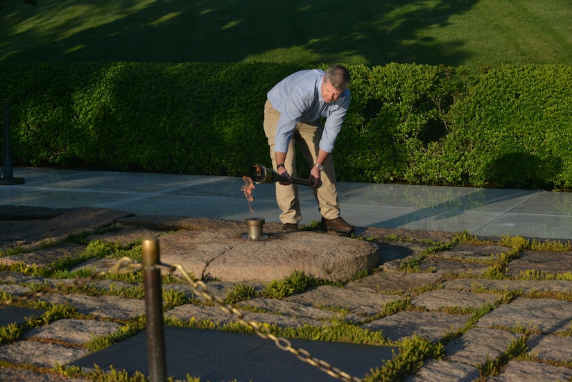 ARLINGTON, Va. -- Randy Barton, an Arlington National Cemetery engineering technician, re-lights the Eternal Flame from the temporary flame at President John F. Kennedy's gravesite on May, 17, 2013 here. The flame has been undergoing repair and upgrade work, which includes installing newly designed burners, a new igniter and new gas and air lines. Underground work continues and is expected to be complete later this month.(U.S. Army Photo/Melissa Bohan)