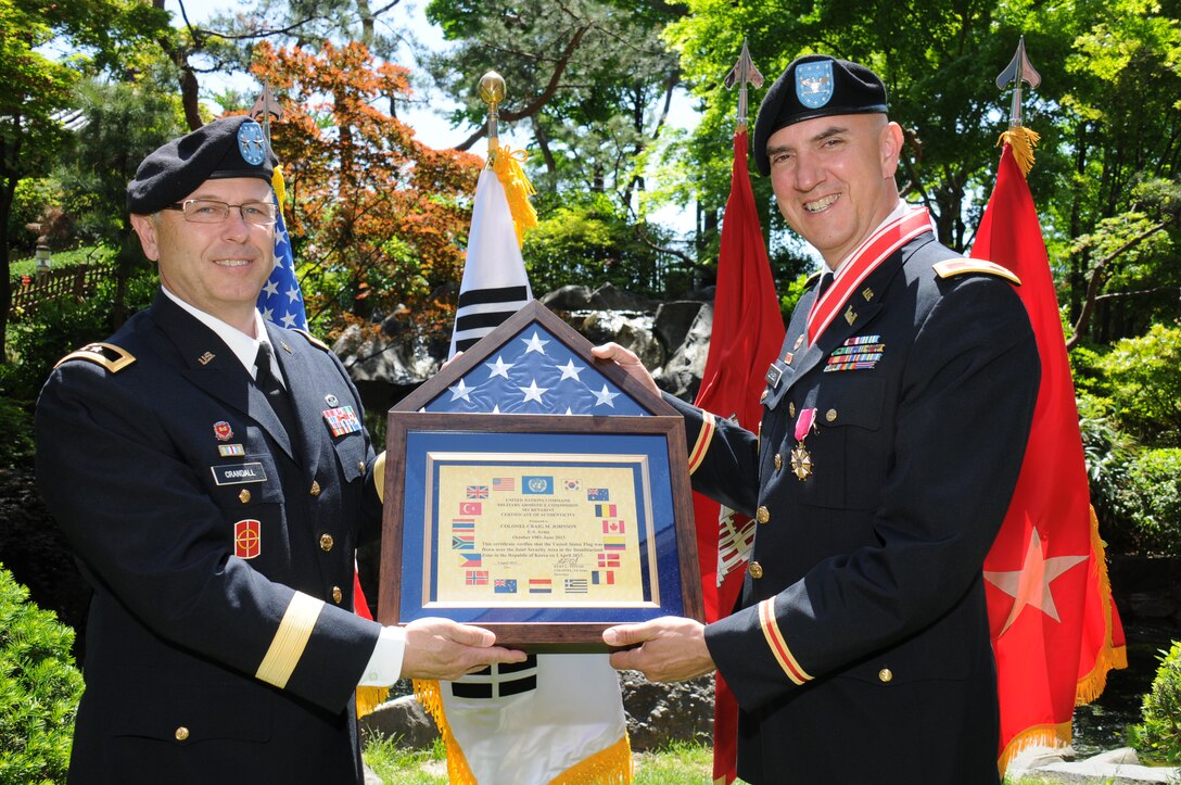 Col. Craig M. Johnson, right, and Maj. Gen. Paul Crandall, hold a flag flown over the Korean Demilitarized Zone during Johnson's retirement ceremony May 16.  Johnson, of the U.S. Army Corps of Engineers Far East District's Korea Program Relocation Office, retired with 32 years of service. Crandall, the U.S. Forces Korea deputy chief of staff for restationing, presented Johnson with a Legion of Merit medal and the Bronze Order of the De Fleury medal.  