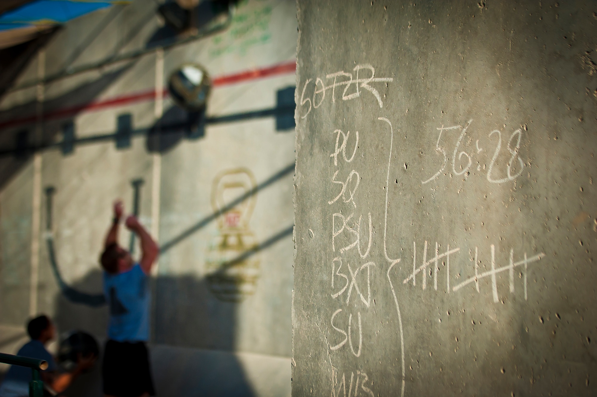Walls chalked with exercises and repetitions surround a group of athletes during a Kandahar CrossFit Hero Workout of the Day at Kandahar Airfield, Afghanistan, May 11, 2013. The WoD was held in honor of U.S. Air Force Capts. Brandon Cyr and Reid Nishizuka, Staff Sgts. Richard Dickson and Daniel Fannin who gave their lives when their MC-12 Liberty aircraft went down April 27 in Southern Afghanistan. (U.S. Air Force photo/Senior Airman Scott Saldukas)