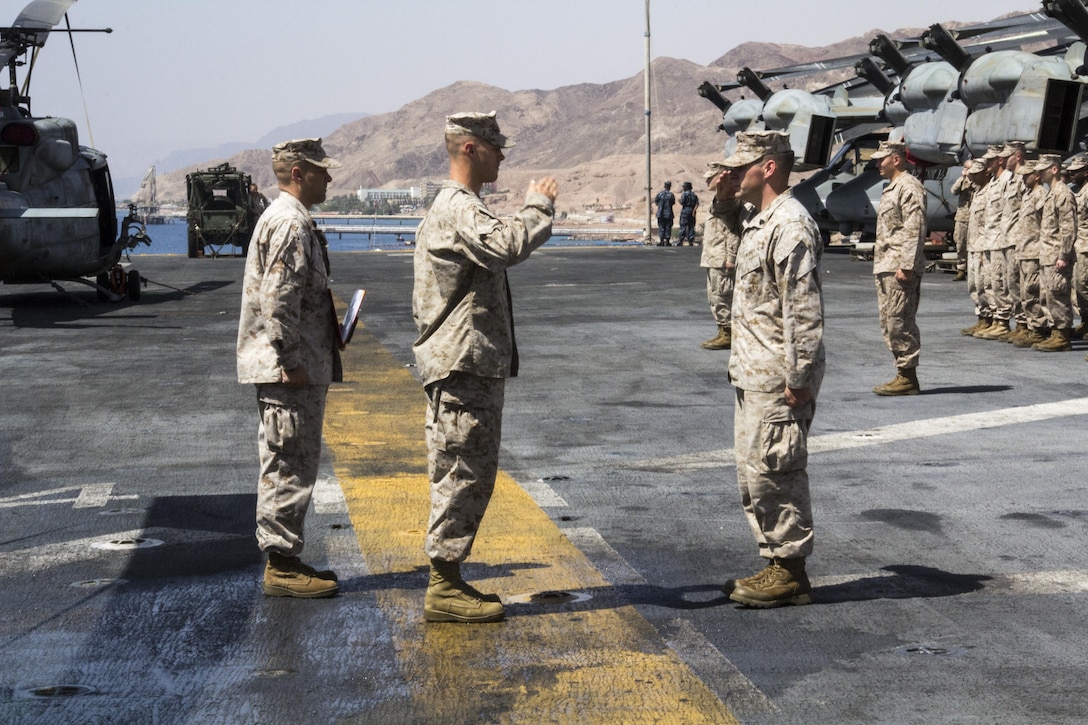 U.S. Marine Sgt. Timothy J. Comeau, Battalion Landing Team 3/2, 26th Marine Expeditionary Unit (MEU), reports to Capt. Jason Kemp, India Company commading officer, during his Purple Heart Award ceremony for wounds received in action Feb. 23, 2011, in Afghanistan on the flight deck of the USS Kearsarge (LHD 3), Eilat, Israel, May 14, 2013. The 26th MEU is deployed to the 5th Fleet area of operations aboard the Kearsarge Amphibious Ready Group. The 26th MEU operates continuously across the globe, providing the president and unified combatant commanders with a forward-deployed, sea-based quick reaction force. The MEU is a Marine Air-Ground Task Force capable of conducting amphibious operations, crisis response and limited contingency operations. (U.S. Marine Corps photograph by Gunnery Sgt. Michael Kropiewnicki/26th MEU Combat Camera/Released)