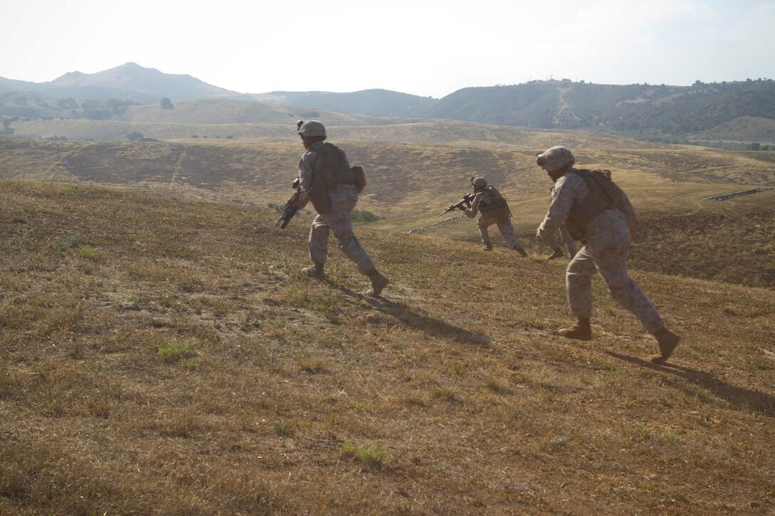 Marines serving with 1st Battalion, 1st Marine Regiment, charge an enemy position during an assault training excercise here, May 15, 2013. The training was designed to give fire team leaders and squad leaders practice leading their Marines in combat. The Marines rushed more than 200 yards up a hill, while suppressing the enemy position.