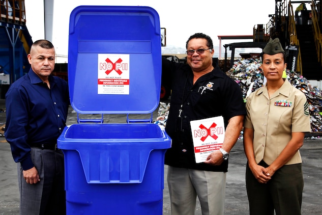 Al Parra, left, Charles Bradshaw, middle, GySgt. Tansey D. Olson, right, take a photo with a large sticker that will be placed on blue recycling bins around base, at the recycling center here May 17. The sticker is the newest method of protecting personal identifiable information around the base. Parra is the Privacy Act coordinator for Marine Corps Installations West – Marine Corps Base Camp Pendleton. Bradshaw is the Base Recycling Manager for Camp Pendleton. Olson is the adjutant chief for Marine Corps Installations West – Marine Corps Base Camp Pendleton. 