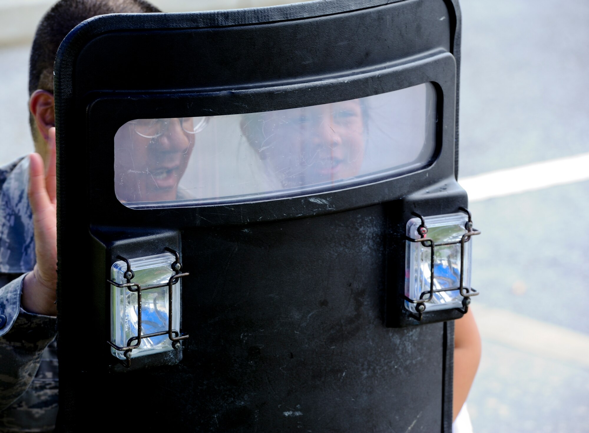 U.S. Air Force Chief Master Sgt. Ami Masaniai, 18th Security Forces Squadron security forces manager, explains to his daughter, Gracie Masaniai, the purpose of a riot shield during the open house portion of Police Week on Kadena Air Base, Japan, May 15, 2013. Police Week is a week dedicated to the memory of fallen civilian and military police officers. (U.S. Air Force photo by Airman 1st Class Justin Veazie/Released)