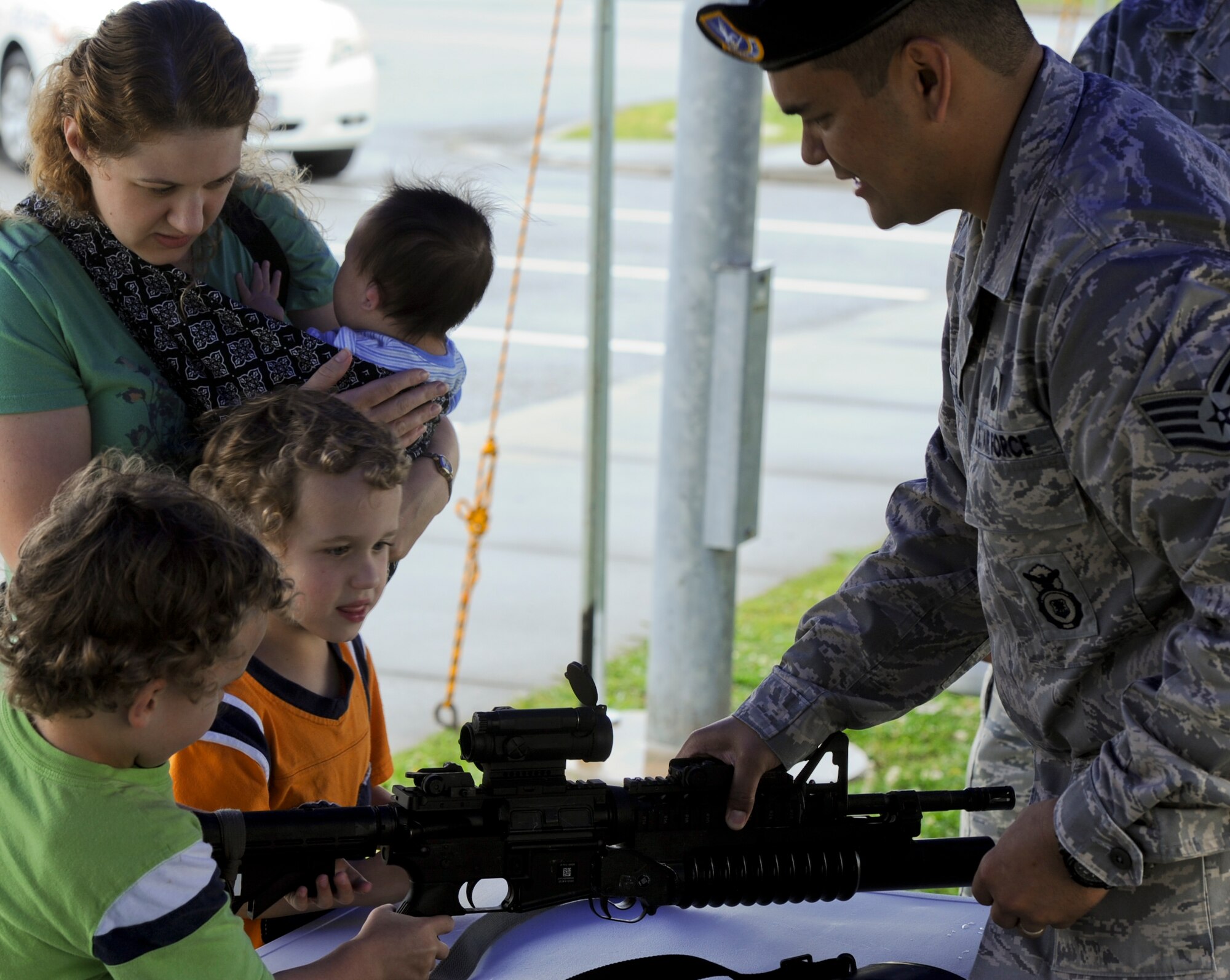 An 18th Security Forces Squadron member speaks to family members about M-16As and M-4s during the open house portion of Police Week on Kadena Air Base, Japan, May 15, 2013. Police Week is a week to show what military police officers do on a daily basis. (U.S. Air Force photo by Airman 1st Class Justin Veazie/Released)