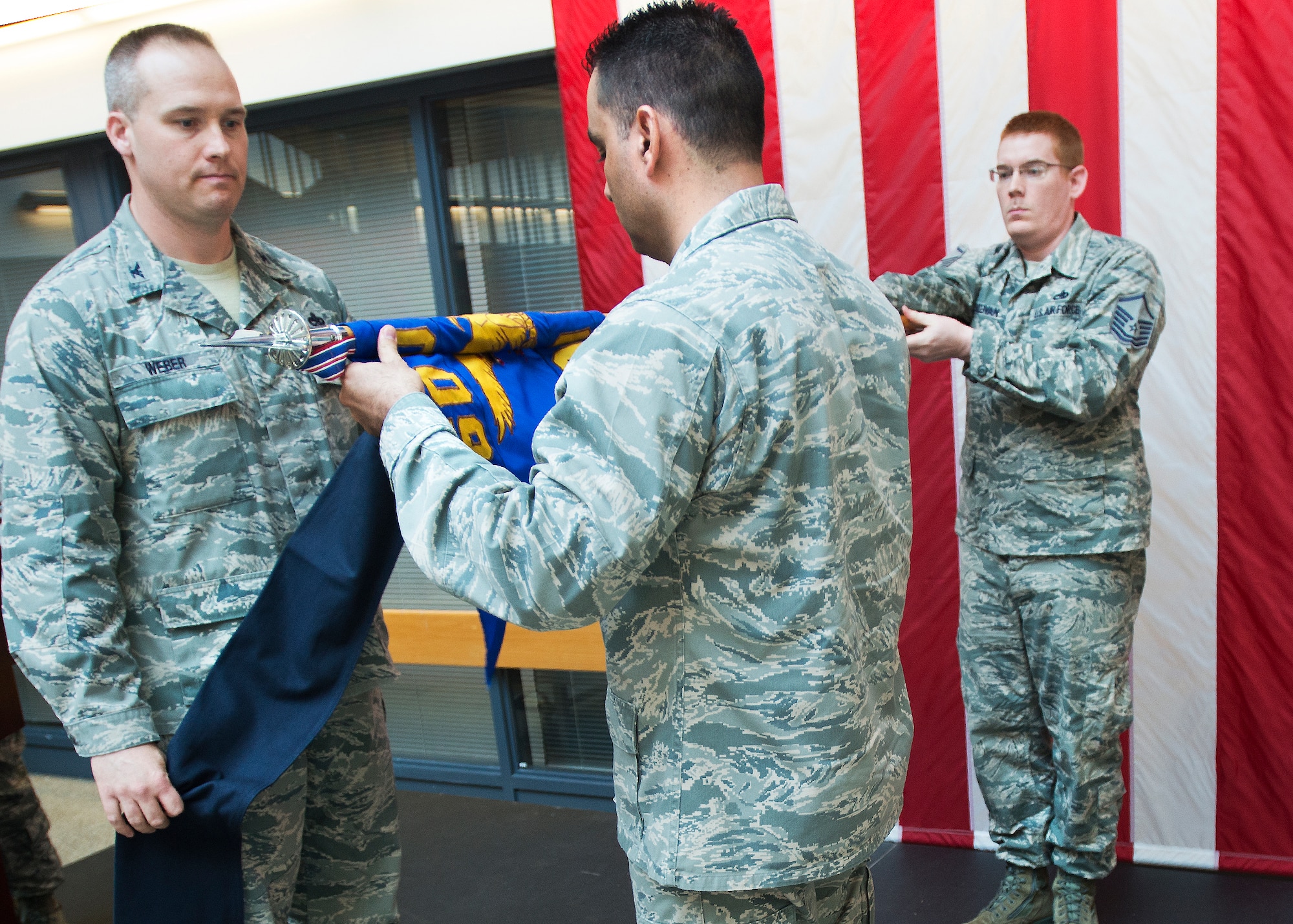 Col. Mark Weber, 60th Maintenance Group commander, looks on as Lt. Col. David Bennet, former 60th Maintenance Operations Squadron commander, folds the unit’s guideon fl ag during an inactivation ceremony May 10 at the 60th MXG atrium. (U.S. Air Force photo/T.C. Perkins)