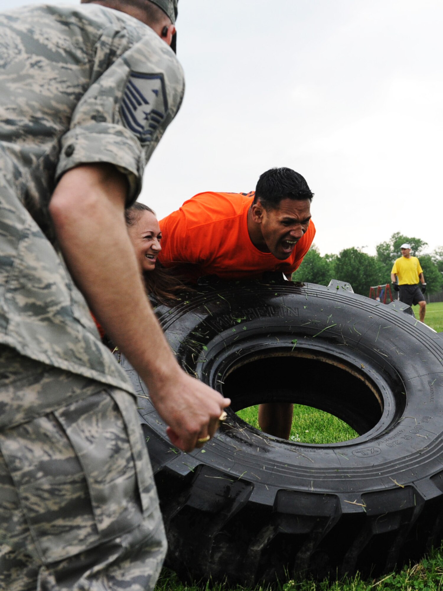 Members of the 635th Supply Chain Operations Group team, Capt. Sarah Bennett and Tech. Sgt. Sydney Kneubuhl, are yelled at by their first sergeant, Master Sgt. Robert Fitzpatrick, to try to flip the tire faster at the Airman Leadership School field May 17. Cash prizes of $1,000, $750, $550, $350, and $250 was awarded to the top five teams. (U.S. Air Force photo/Senior Airman Jake Eckhardt)