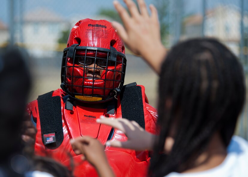U.S. Air Force Staff Sgt. Kori Trimble, 7th Security Forces Squadron (SFS), stands ready as Dyess youth volunteer for the chance to restrain her during a National Police Week event May 14, 2013, at Dyess Air Force Base, Texas. In 1962, President John F. Kennedy proclaimed May 15 as National Peace Officers Memorial Day and the calendar week in which May 15 falls, as National Police Week. The week pays special recognition to those law enforcement officers who have lost their lives in the line of duty for the safety and protection of others. The 7th SFS held a jail-and-bail fundraiser, vehicle display, weapons display and bike rodeo throughout the week. (U.S. Air Force photo by Airman 1st Class Damon Kasberg/ Released)