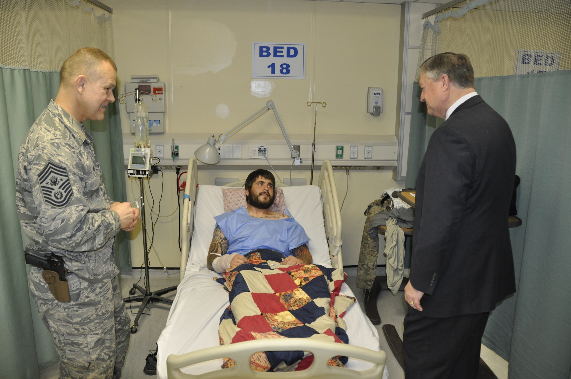 James Roy, former Chief Master Sergeant of the Air Force and Michael Donley, Secretary of the Air Force, greet Staff Sgt. Zachary Cahall, 436th Security Forces Squadron dog handler, at his bed in the hospital Dec. 29, 2012, at Bagram Air Base, Afghanistan. Cahall was recovering from wounds he received in an incident that happened the previous day near Shindand Air Base in Western Afghanistan. (Courtesy photo)