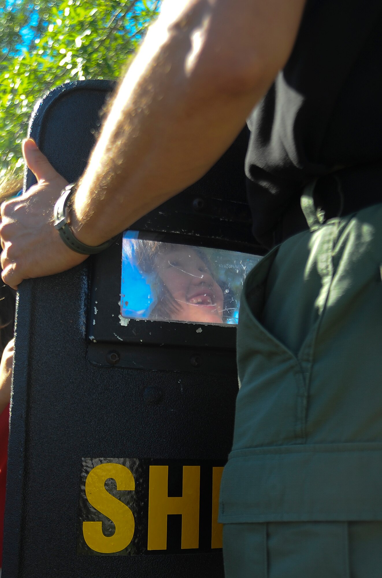 Elizabeth Hanson, 1st Grader at Tinker Elementary School, peers through a Hillsborough County Sherriff’s Department riot shield during the annual National Police Officers Week show-and-tell event on May 15, 2013 at MacDill Air Force Base, Fla. Each year, as part of National Police Officer Week, members from the 6th Security Forces Squadron and local police departments put on demonstrations depicting the different aspects involved in public safety. (U.S. Air Force photo by Staff Sgt. Brandon Shapiro/ released)