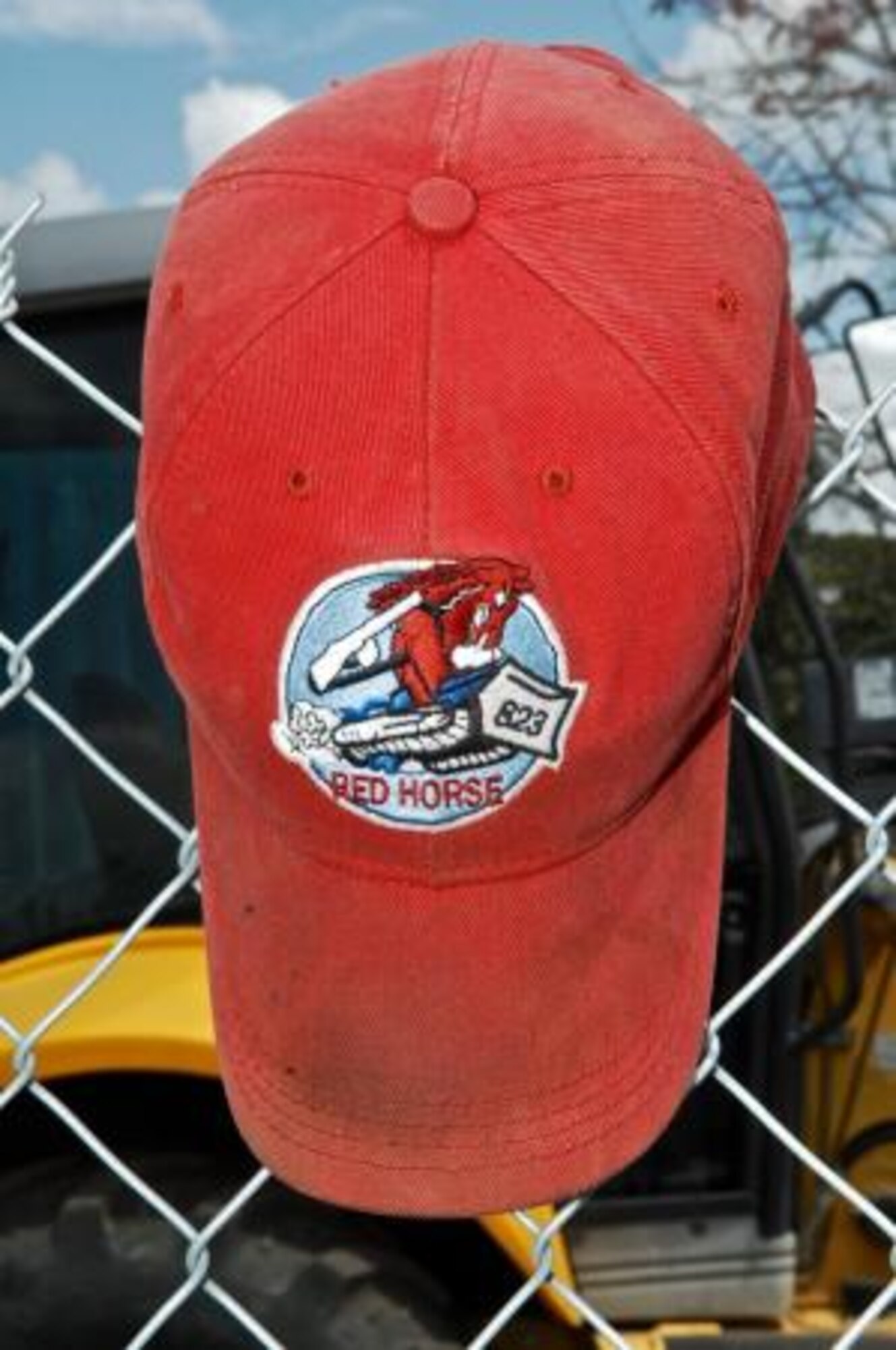 An 823rd Rapid Engineer Deployable Heavy Operational Repair Squadron Engineers hat hangs on a fence at the Crooked Tree Government Primary School construction site. The red hat is a distinctive symbol worn by all RED HORSE airmen.
