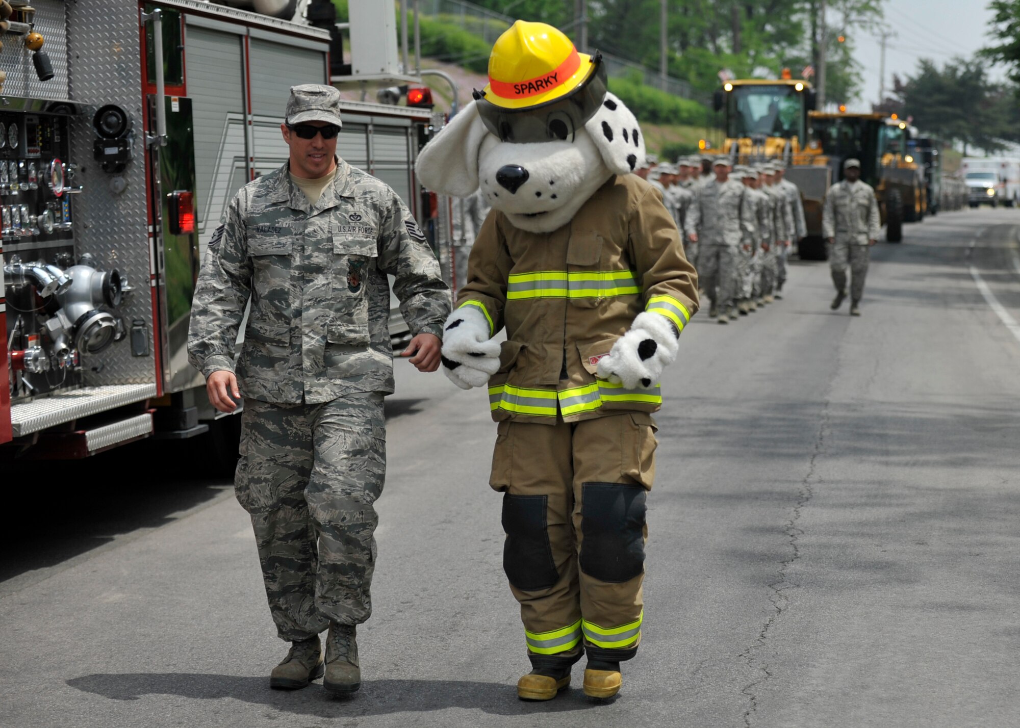 Staff Sgt. Jacob Valadez, 51st Civil Engineer Squadron fire protection crew chief, and Sparky the Fire Dog walk in the Veterans of Foreign Wars Armed Forces Day Parade at Osan Air Base, Republic of Korea, May 18, 2013. Sparky greeted numerous children that were in attendance at the parade. (U.S. Air Force photo/Senior Airman Siuta B. Ika)