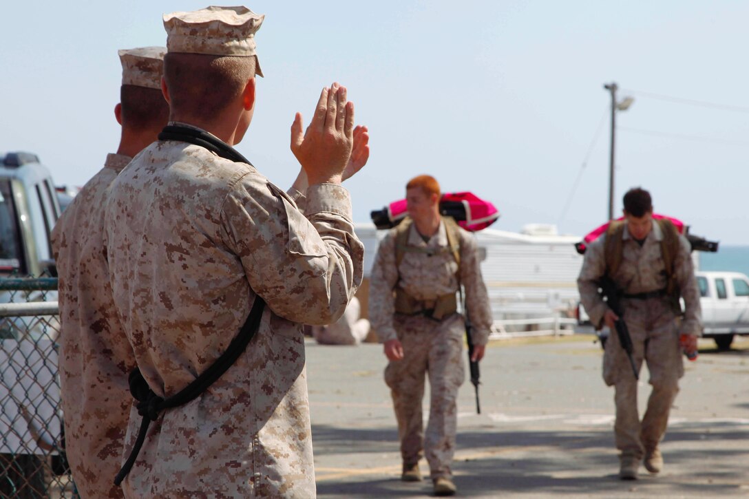 Basic Reconnaissance Course students applaud Sgt, Johnathan Bumpus and Sgt. Alexander Hale as they cross the finish line of the 5th Annual Recon Challenge award ceremony here May 17. The challenge consisted of a 2,000-meter swim, calisthenics tests and other skill based events.
