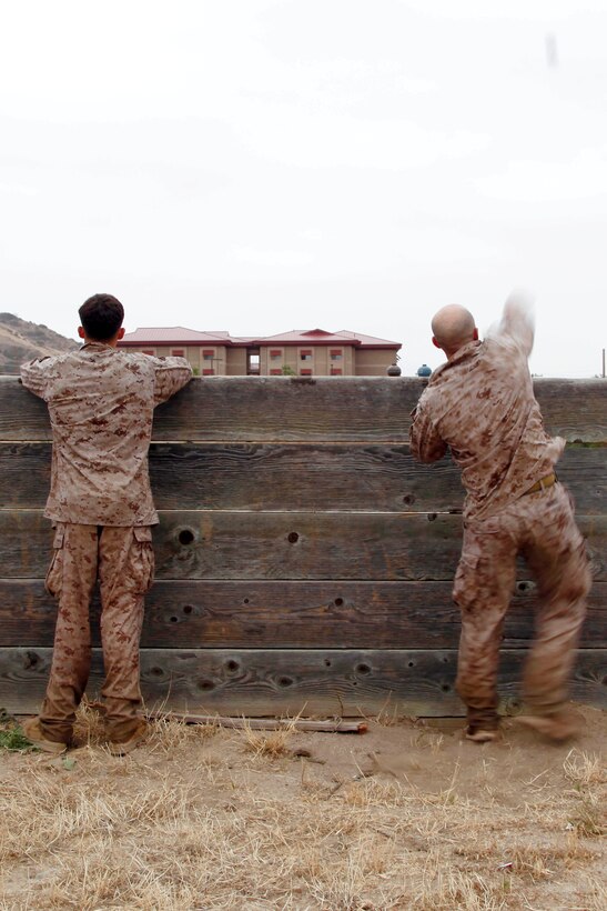 Master Sgt. Vincent Marzi, right, tosses a blue body dummy grenade during the 5th Annual Recon Challenge here May 17. The challenge consisted of a 2,000-meter swim, calisthenics tests and other skill based events. 

