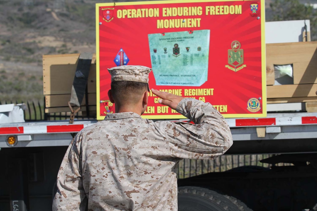A Marine serving with 5th Marine Regiment, 1st Marine Division, salutes as the regiment's Operation Enduring Freedom memorial arrives at Camp San Mateo here, May 20, 2013. Approximately 300 Marines lined San Mateo Road, saluting as the memorial plaque passed by to its final location. The riders escorted the 7-ton Barre granite memorial from Barre, Vt., to Camp Pendleton over the course of 10 days.