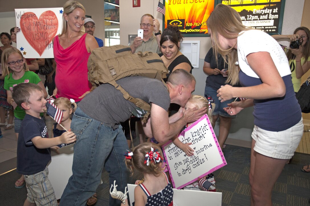 Sergeant Joseph McNichols, an operations specialist with Marine Attack Squadron 513 aboard Marine Corps Air Station Yuma, Ariz., kisses his children for the first time after a 6-month deployment with the 31st Marine Expeditionary Unit. The Marines from VMA-513, who returned home to MCAS Yuma, May 18, were operating in Japan and aboard the USS Bonhomme Richard in the North Pacific Ocean since December of last year.  This marks the final adventure for the VMA-513 Flying Nightmares, as the Squadron is slated for decommissioning this summer.