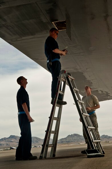 Staff Sgt. Steven Lazarowitz looks for a hydraulic leak on a B-1B Lancer as Airman 1st Class Branden Lane and Senior Airman Cameron Hylan wait to see if help is needed May 21, 2013, at Nellis Air Force Base, Nev. Intact hydraulic lines are essential for jets to maintain full maneuverability. (U.S. Air Force photo/Senior Airman Daniel Hughes) 

