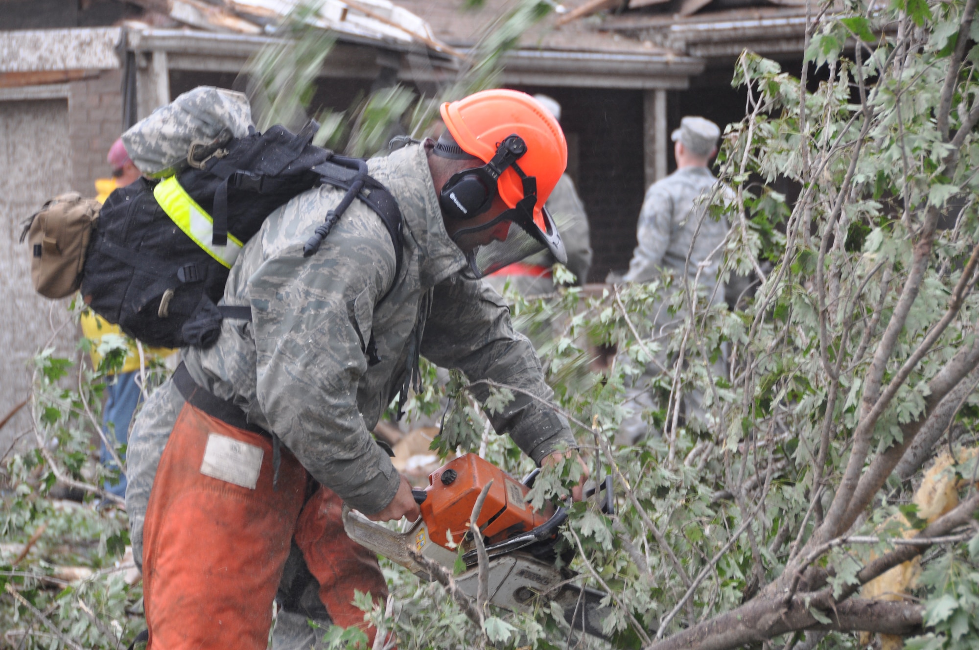 A military member cuts trees that were brought down on homes after a tornado hit the town of Moore, Okla. May 20, 2013.  (U.S. Air Force photo by Maj. Jon Quinlan)