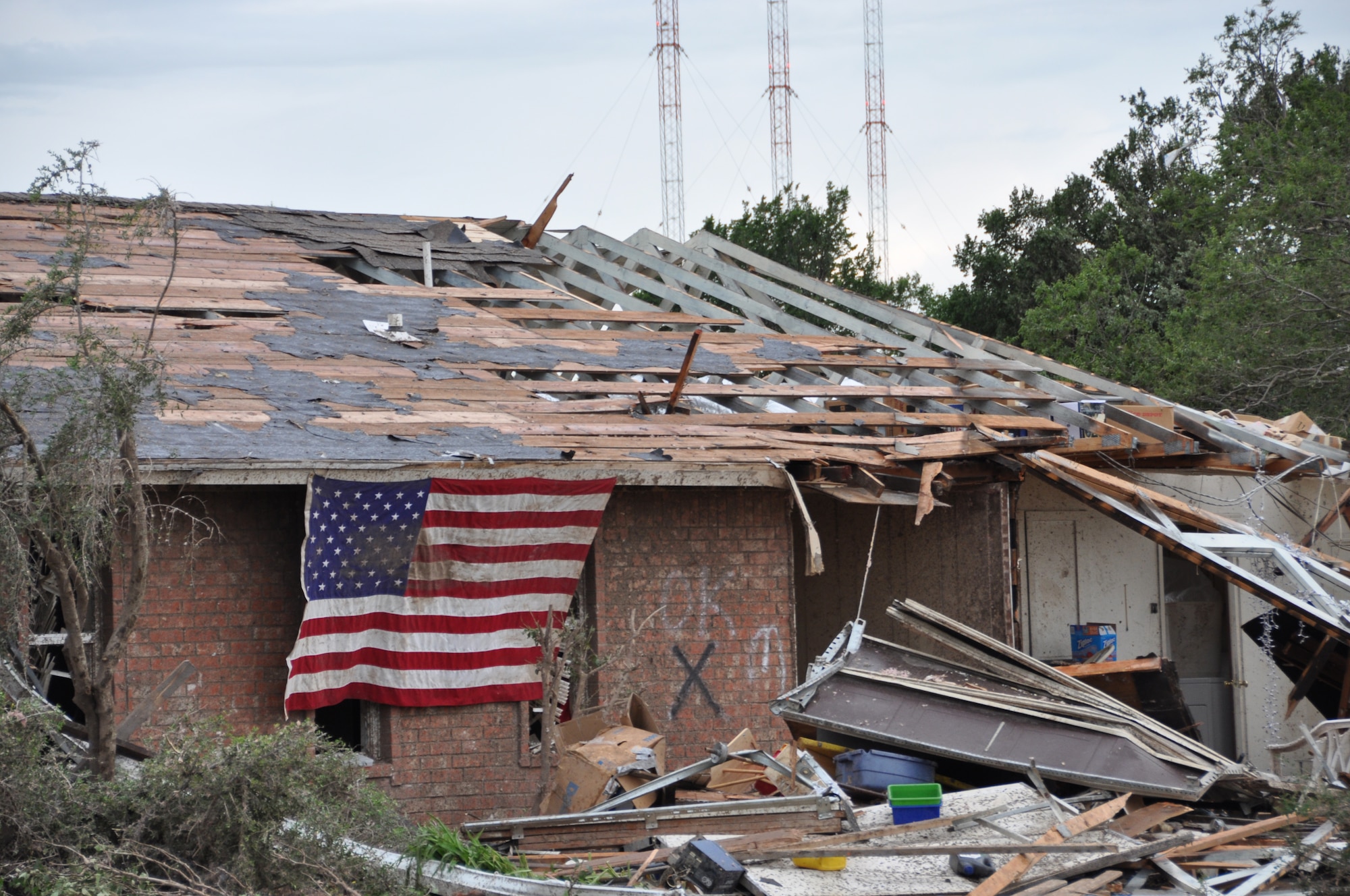 A United States flag hangs from a home devastated by a tornado that hit the town of Moore; Okla. May 20; 2013 near Tinker Air Force Base. (U.S. Air Force photo by Maj. Jon Quinlan)