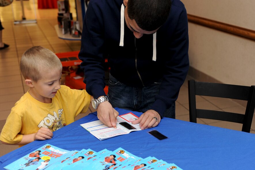 Seth Espitia (left) stamps his fingerprints at the child identification booth in The Exchange at Ellsworth Air Force Base, S.D., May 11, 2013. Members of the 28th Security Forces Squadron hosted numerous events to educate Airmen and their families about security and police work as part of Police Week. (U.S. Air Force photo by Airman 1st Class Anania Tekurio/Released)