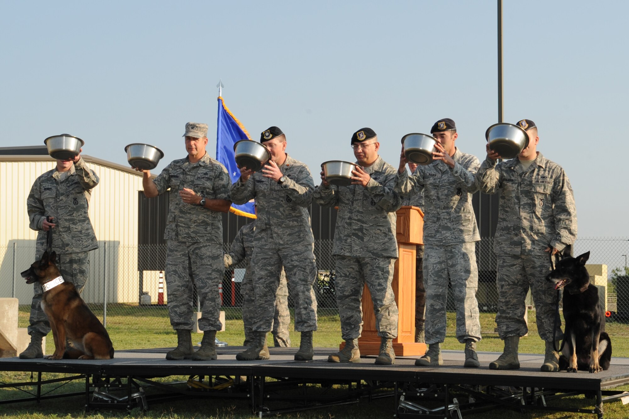 GOODFELLOW AIR FORCE BASE, Texas--Col. Paul Bugenske, 17th Mission Support Group commander, and 17th Security Forces Squadron members drink from charged water bowls for the ultimate toast during 17th SFS military working dogs Karin and Longo’s retirement ceremony at the base kennel, May 14. The ceremony recognized Karin and Longo’s active duty commitment to the U.S. Air Force. (U.S. Air Force photo/ Staff Sgt. Laura R. McFarlane)