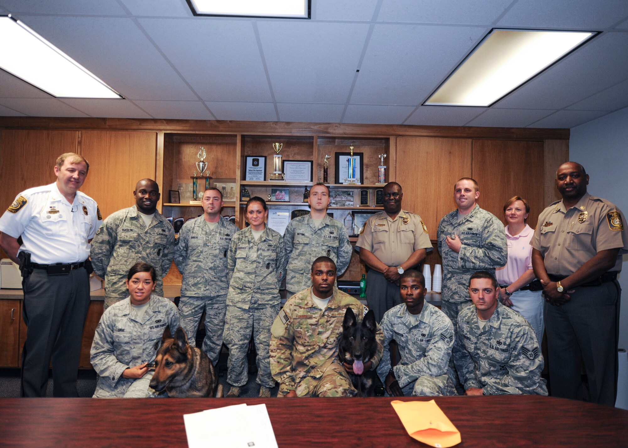 Airmen with the 23d Security Forces Squadron and 823d Base Defense Squadron Military Working Dog units, pose for a group photo with members of the Valdosta Police Department (VPD) in Valdosta, Ga., May 17, 2013. On April 24, 2013, the VPD responded to a bomb threat was called into a local high school and requested support from Moody personnel. All responding agencies were coined as a token of the VPD’s appreciation for their help with the incident. (U.S. Air Force photo by Senior Airman Eileen Meier/Released)