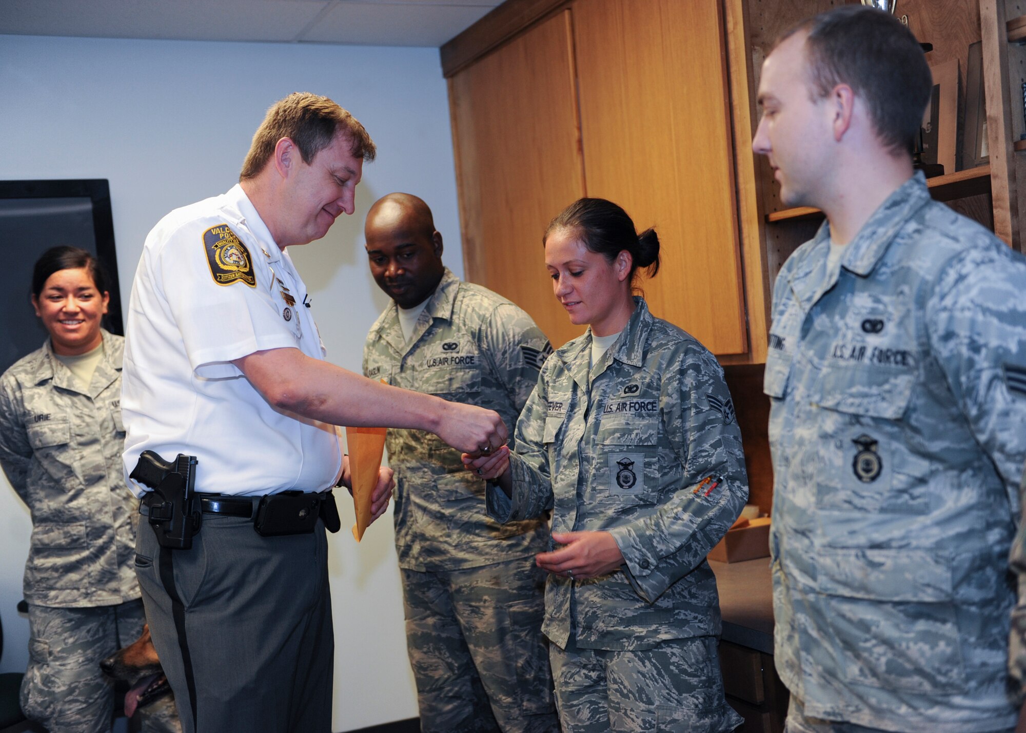 Brian Childress, Valdosta Police Department (VPD) chief of police, coins members of the 23d Security Forces Squadron and 823d Base Defense Squadron Military Working Dog units, at the VPD May 17, 2013. Moody personnel were called upon for support during a bomb threat at a local high school April 24, 2013, and were coined as a token of appreciation from the VPD. (U.S. Air Force photo by Senior Airman Eileen Meier/Released)