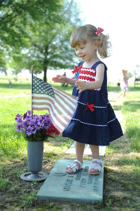 Elle Cronk, the great-great-niece of 2nd Lt. George Whiteman, plays at his graveside before the 25th annual wreath-laying ceremony May 18, 2013, in Sedalia, Mo. Nearby Whiteman Air Force Base was named after the lieutenant, who was only 22 years old when he was one of the first Airmen to be killed during World War II. (U.S. Air Force photo by Senior Airman Brigitte N. Brantley/Released)