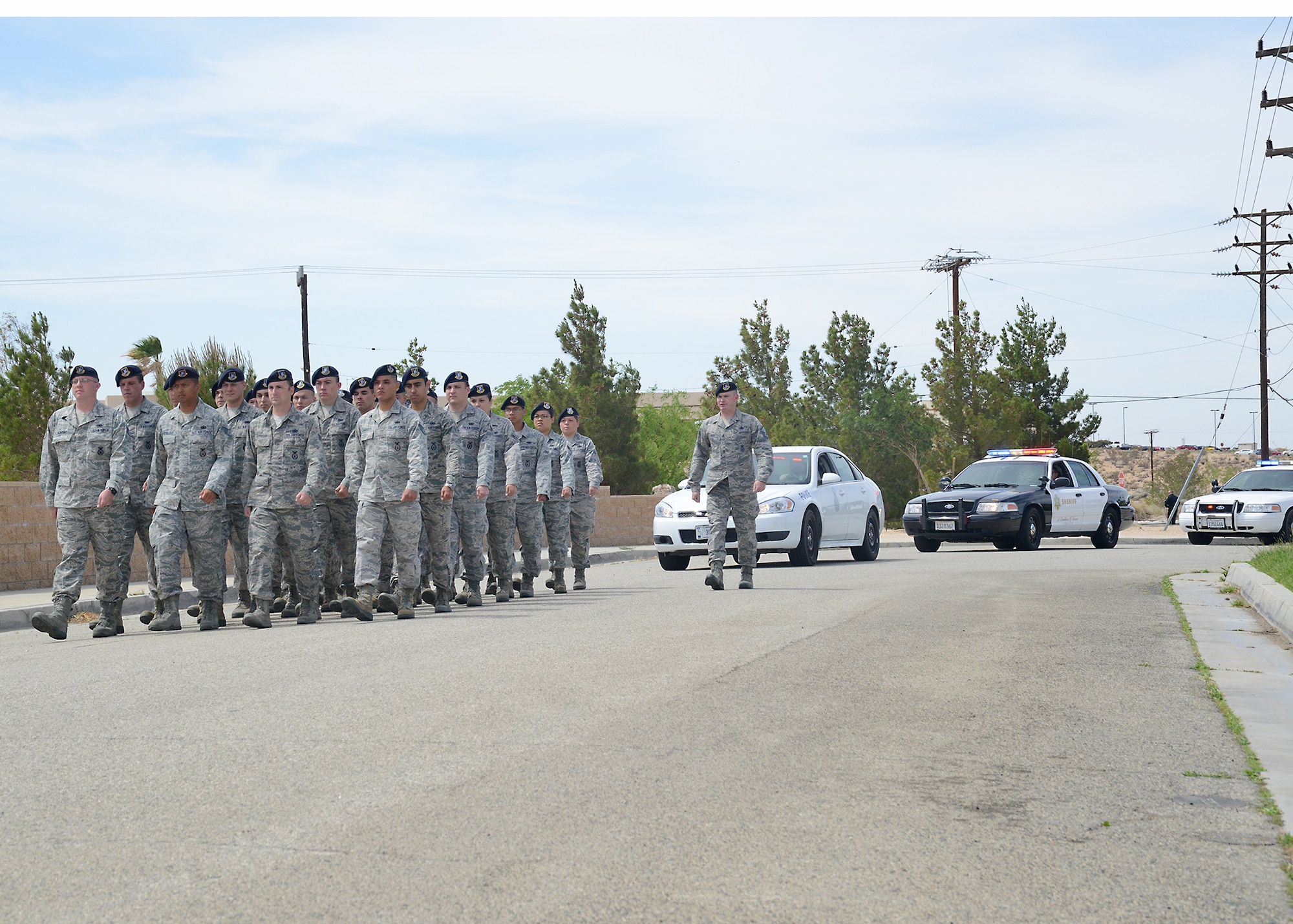 Airmen from the 412th Security Forces Squadron march to the End of Watch Ceremony with local law enforcement vehicles following in procession. (U.S. Air Force photo by Kenji Thuloweit)