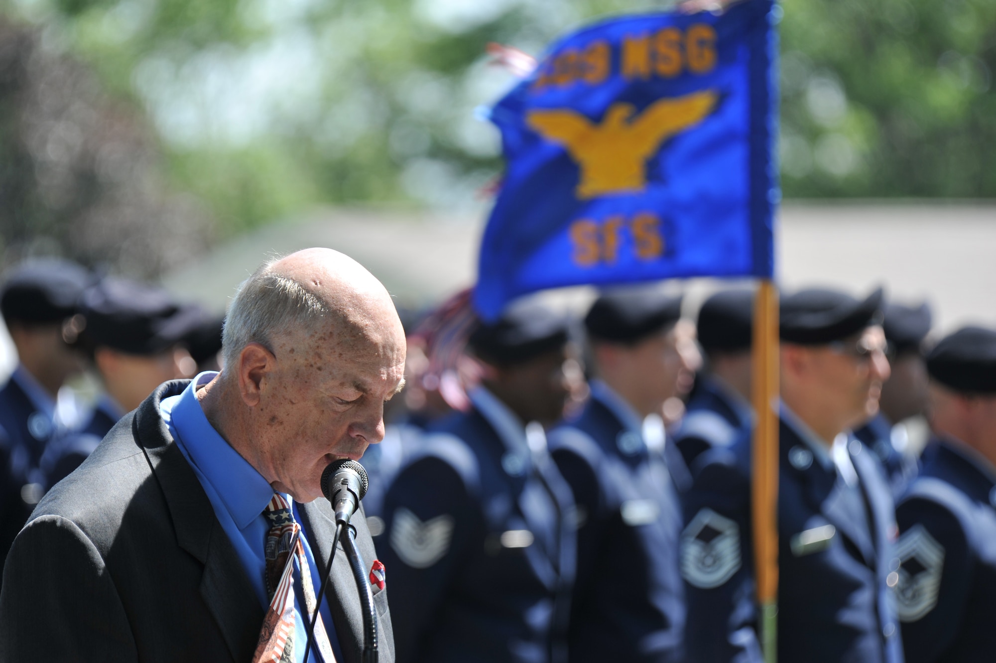 Dave Rouchka, wreath-laying ceremony event coordinator, talks about 2nd Lt. George Whiteman’s legacy during a ceremony May 18, 2013, in Sedalia, Mo., as members of the 509th Security Forces Squadron stands at attention in the background. The 509th SFS and Sedalia are “sister cities” and support each other in community events like this one. (U.S. Air Force photo by Senior Airman Brigitte N. Brantley/Released)