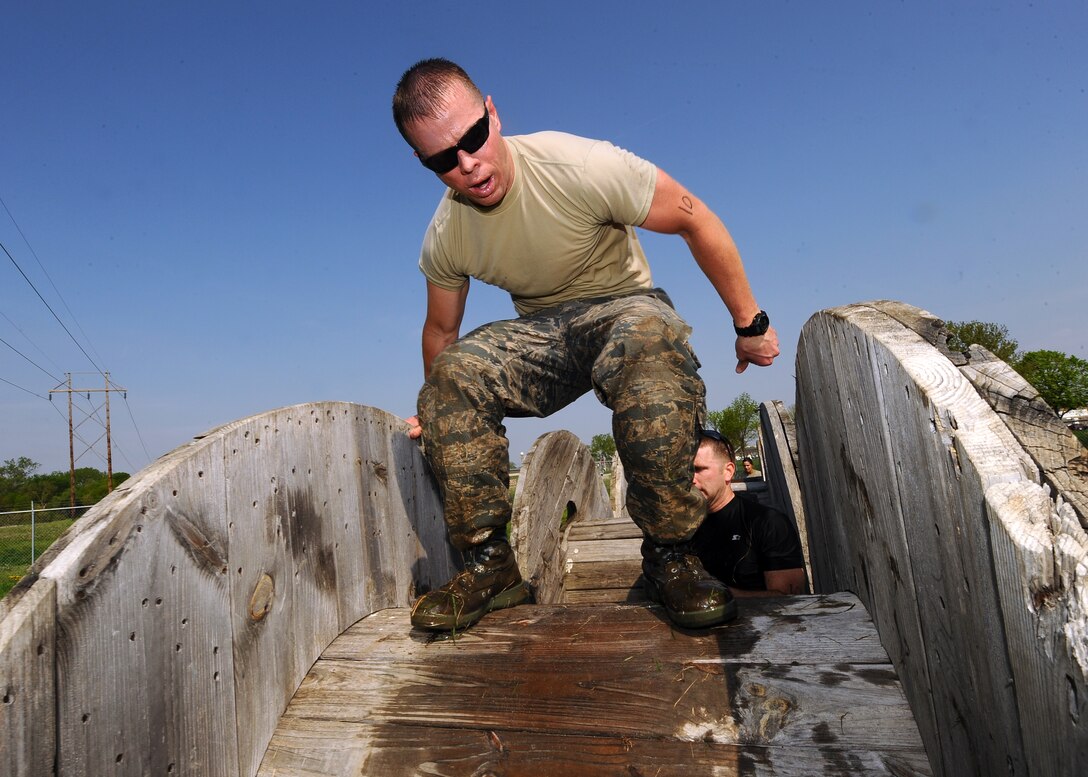 U.S. Air Force Captain Hank Chilcoat, Flight Commander, Weather Intelligence Flight, 2D Weather Squadron, climbs over a cable spindle while leading his team through the Police Week Evasion Challenge obstacle course held on May 16, Offutt Air Force Base, Neb. During National Police Week at Offutt there was also a weapons display, golf tournament and a retreat ceremony. (U.S. Air Force photo by Josh Plueger)