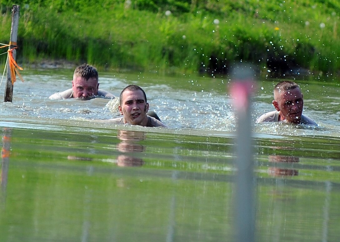 The 55th Logistics Readiness Squadron’s four-man team swim through a flooded drainage ditch as part of the Police Week Evasion Challenge obstacle course held on May 16, Offutt Air Force Base, Neb. Teamwork was an essential component to completing the course that forced the teams to band together to complete more than three miles of obstacles.  (U.S. Air Force photo by Josh Plueger/Released)