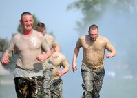 The 55th Logistics Readiness Squadron’s four-man team gets hit with a fire hose as they near the end of the Police Week Evasion Challenge obstacle course held on May 16, Offutt Air Force Base, Neb. The Evasion Challenge took teams through a heavily wooded area where they ran through mud ruts, swam through a drainage ditch, and low crawled under a canopy prior to finishing the race. (U.S. Air Force photo by Josh Plueger/Released)