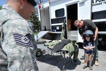 U.S. Air Force Tech. Sgt. Michael Ramsey, 55th Security Forces Squadron, watches Sgt. Matt Manhart, Omaha Police Department bomb response team, place a helmet on 5-year-old Joseph Ramsey during Police Week outside the Base Exchange on Offutt Air Force Base, Neb., May 15. (U.S. Air Force photo by Charles Haymond/Released)