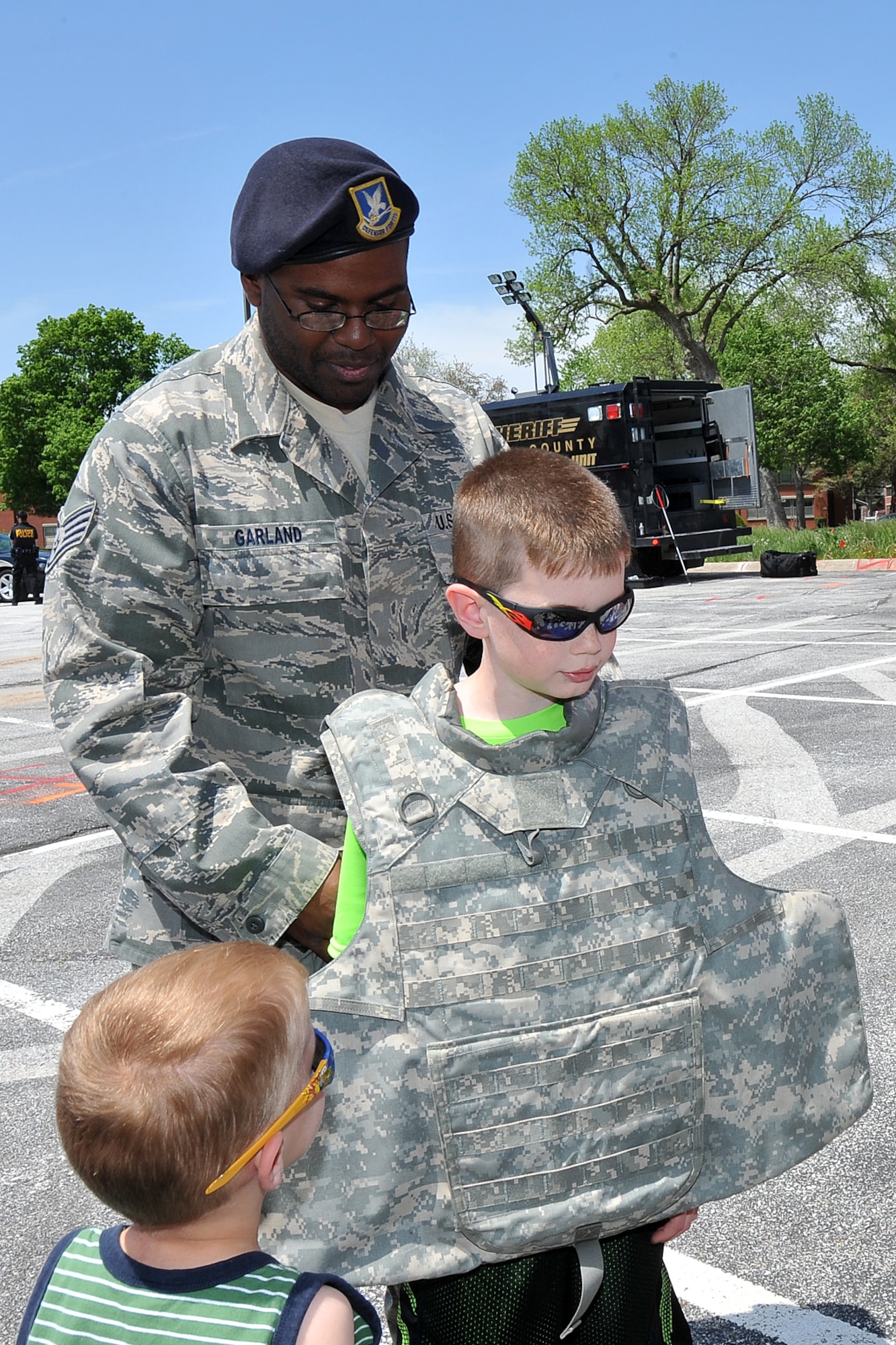 U.S. Air Force Staff Sgt. Dorian Garland, 55th Security Forces Squadron, places a tactical vest on Ryan Rowe, 8-year-old son of U.S. Air Force Lt. Col.  Ryan Rowe, 55th Aircraft Maintenance Squadron commander, during Police Week outside the Base Exchange on Offutt Air Force Base, Neb., May 15. In 1962, President John F. Kennedy signed a proclamation which designated May 15 as Peace Officers Memorial Day and the week in which that date falls as Police Week. (U.S. Air Force photo by Charles Haymond/Released)