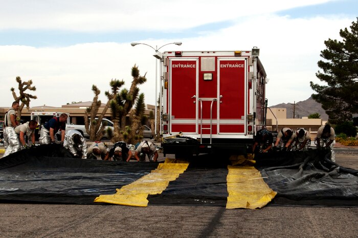 Firefighters from the 99th Civil Engineer Squadron at Nellis Air Force Base set up a mobile decontamination unit as part of an exercise May 16, 2013. The firefighters place the mobile decontamination unit over a tarp to protect the ground from possible contamination. (U.S. Air Force photo by Staff Sgt. Gregory Brook)