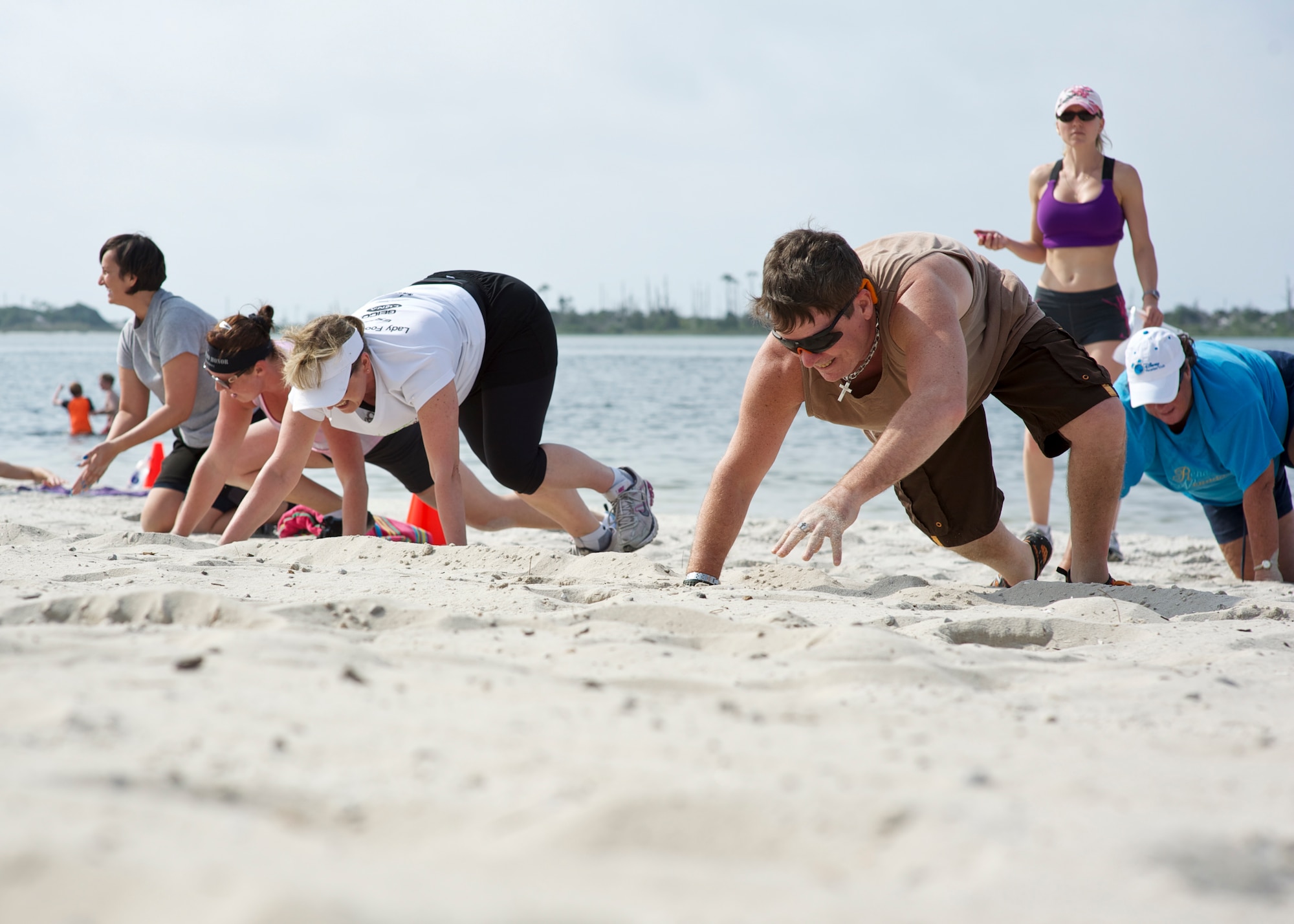 Participants crawl across the beach during beach boot camp at the Soundside Beach on Hurlburt Field Fla., May 18, 2013. The beach boot camp class combined a number of physical challenges and obstacles designed to push people past their physical limits. (U.S. Air Force Photo/ Staff Sgt. John Bainter)